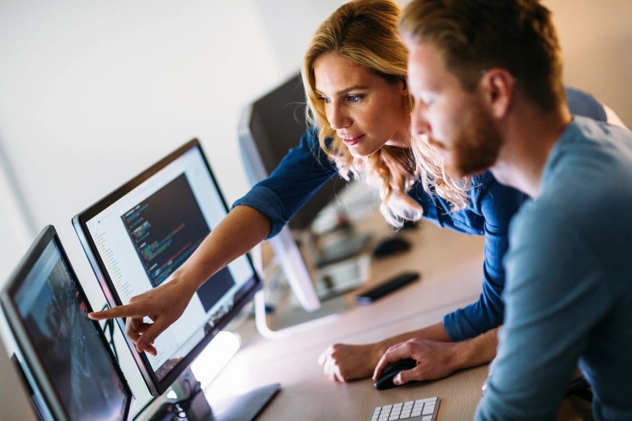 A woman and man working on computers at a desk.