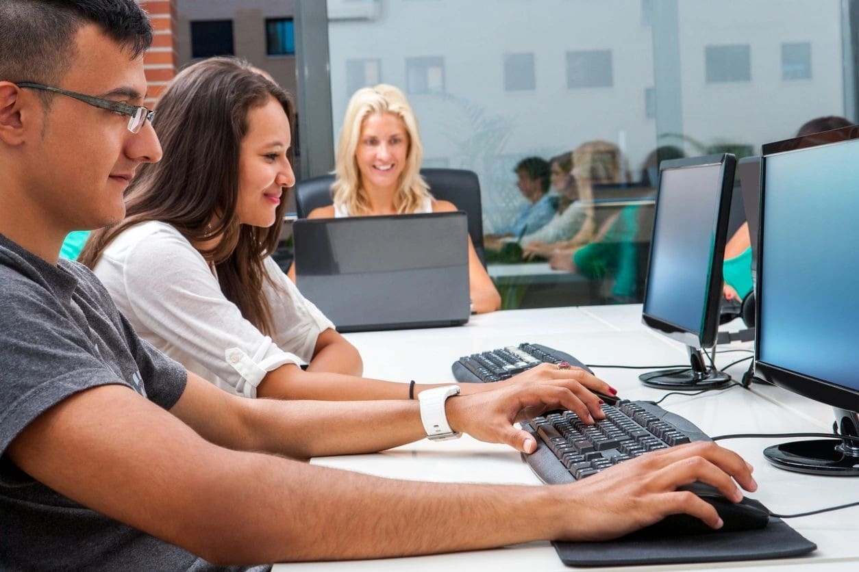 A group of people sitting at tables with computers.