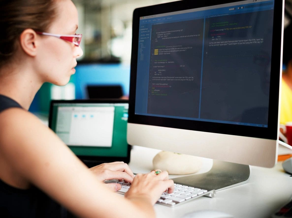 A woman sitting at her computer desk typing.